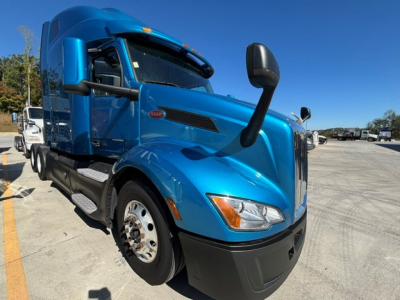 Peterbilt 579 cab-over style blue truck with side mirrors, large fuel tanks, and front bumper; no visible text readable on the image itself.