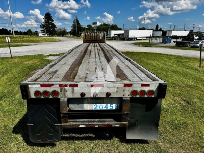 Flatbed trailer rear view showing license plate 20456, taillights, mud flaps, and weathered wooden deck.