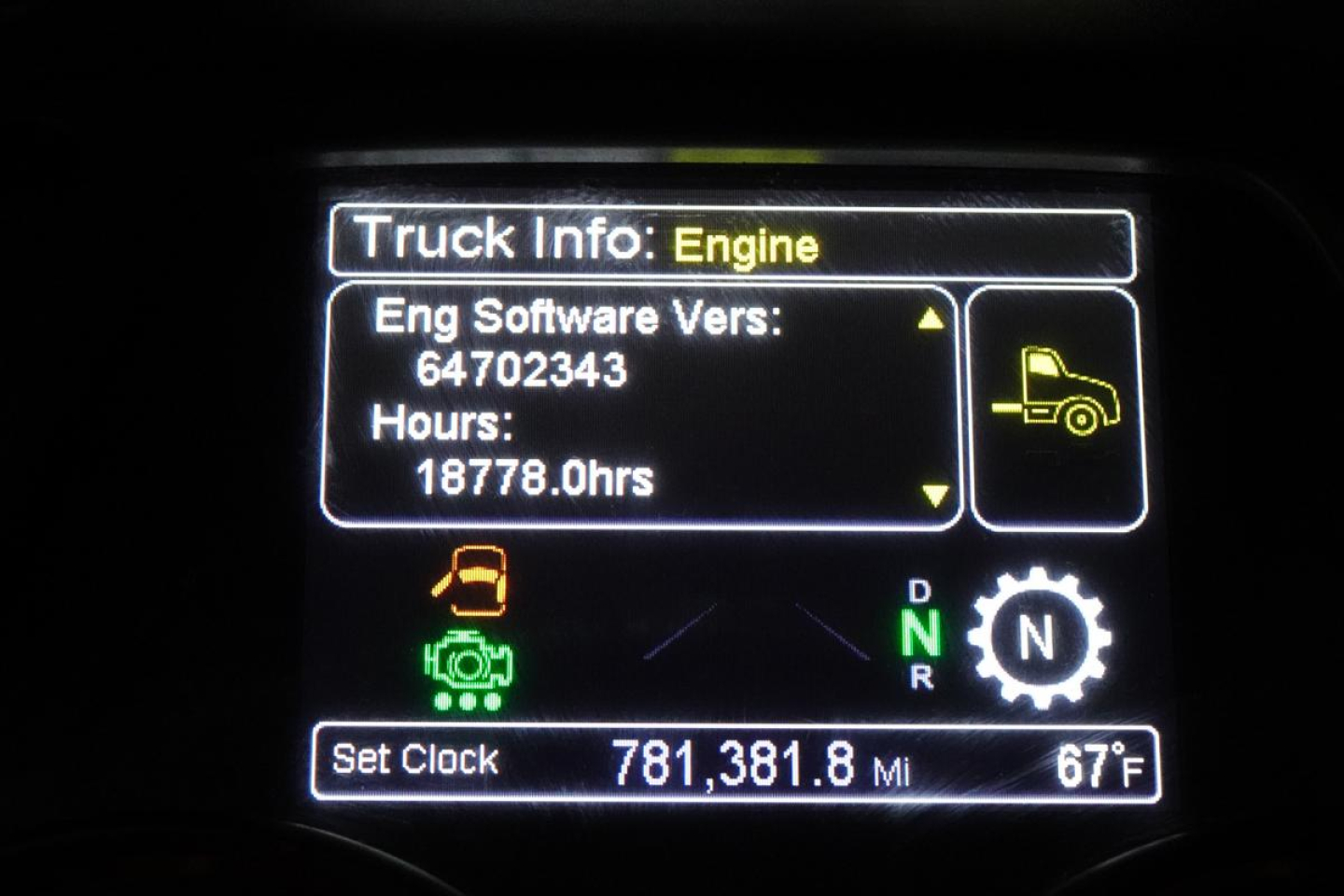 Truck info display screen showing Engine software version 64702343, hours 18778.0, gear indicator with D N R and N highlighted, odometer 781,381.8 miles, ambient 67°F.
