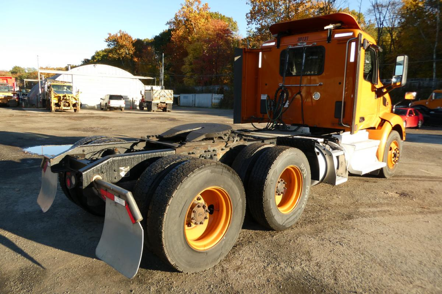 Peterbilt 579 tractor with orange cab, rear view showing dual rear axles and fifth-wheel area; no text clearly visible on panels.
