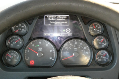  Peterbilt 579 dashboard view with multiple gauges and center display; warning text shows Collision Mitigation System Installed.