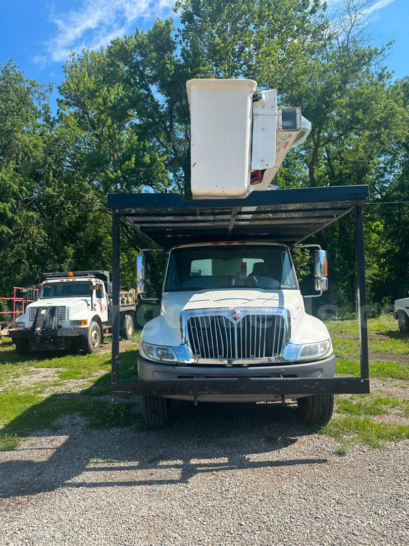 Truck front view of a 2006 International 4300 bucket truck with boom raised in white bucket, grille with International emblem, on a rack over the cab.