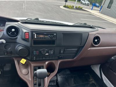 Cab and Chassis interior view of 2025 Hino L7 showing dashboard controls, steering column, center console, gear selector, and cup holders.