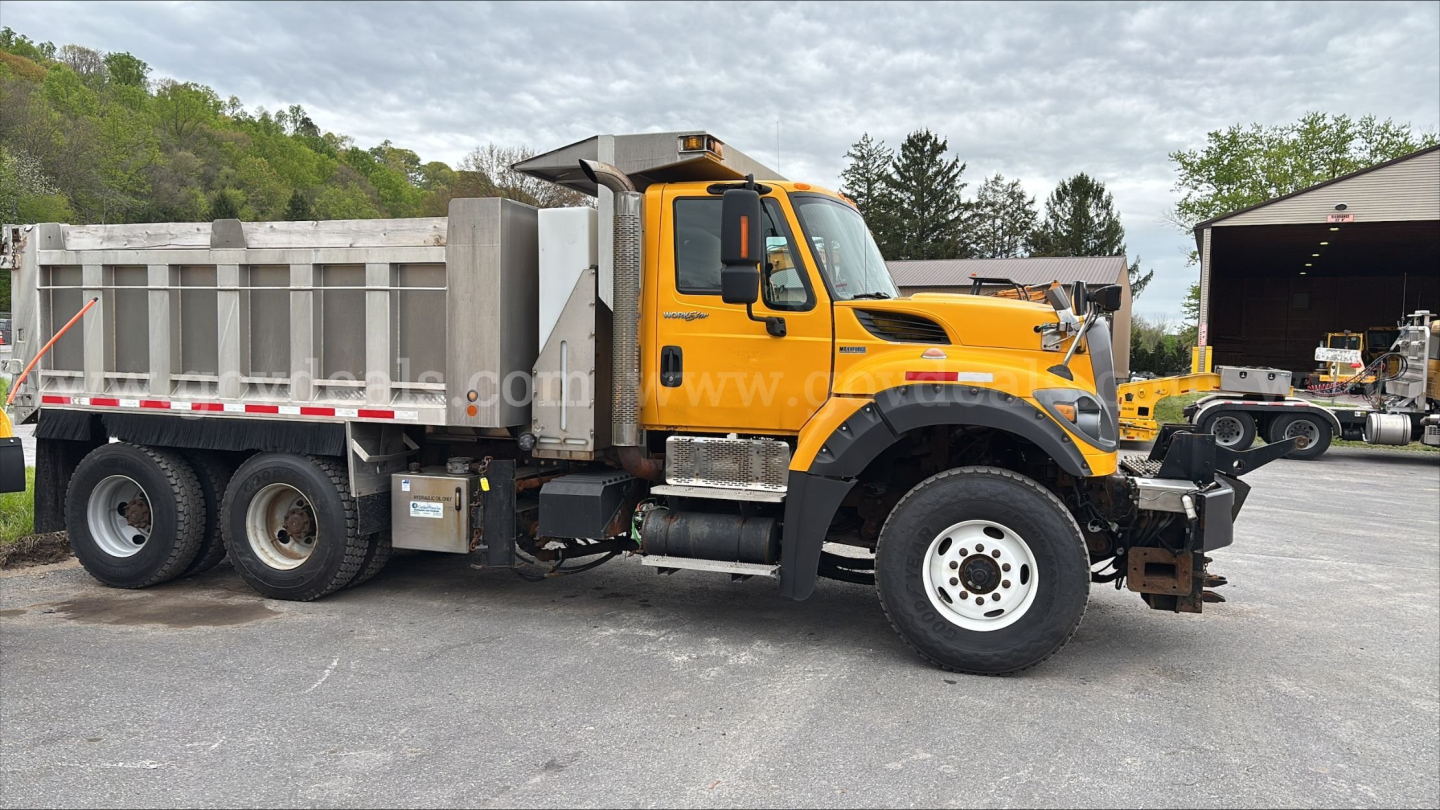 Dump truck 2013 International 7600 in-service with bright yellow cab, large metal dump bed, dual rear axles, side exhaust, and front bumper guards.