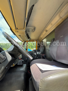 Truck cab interior view of a 2013 International 7600 dump truck showing steering wheel, dashboard, and front seats.
