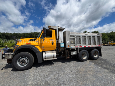 Dump truck side view showing bright orange International 7600 with silver dump bed and six wheels, stock number 30360 in background.