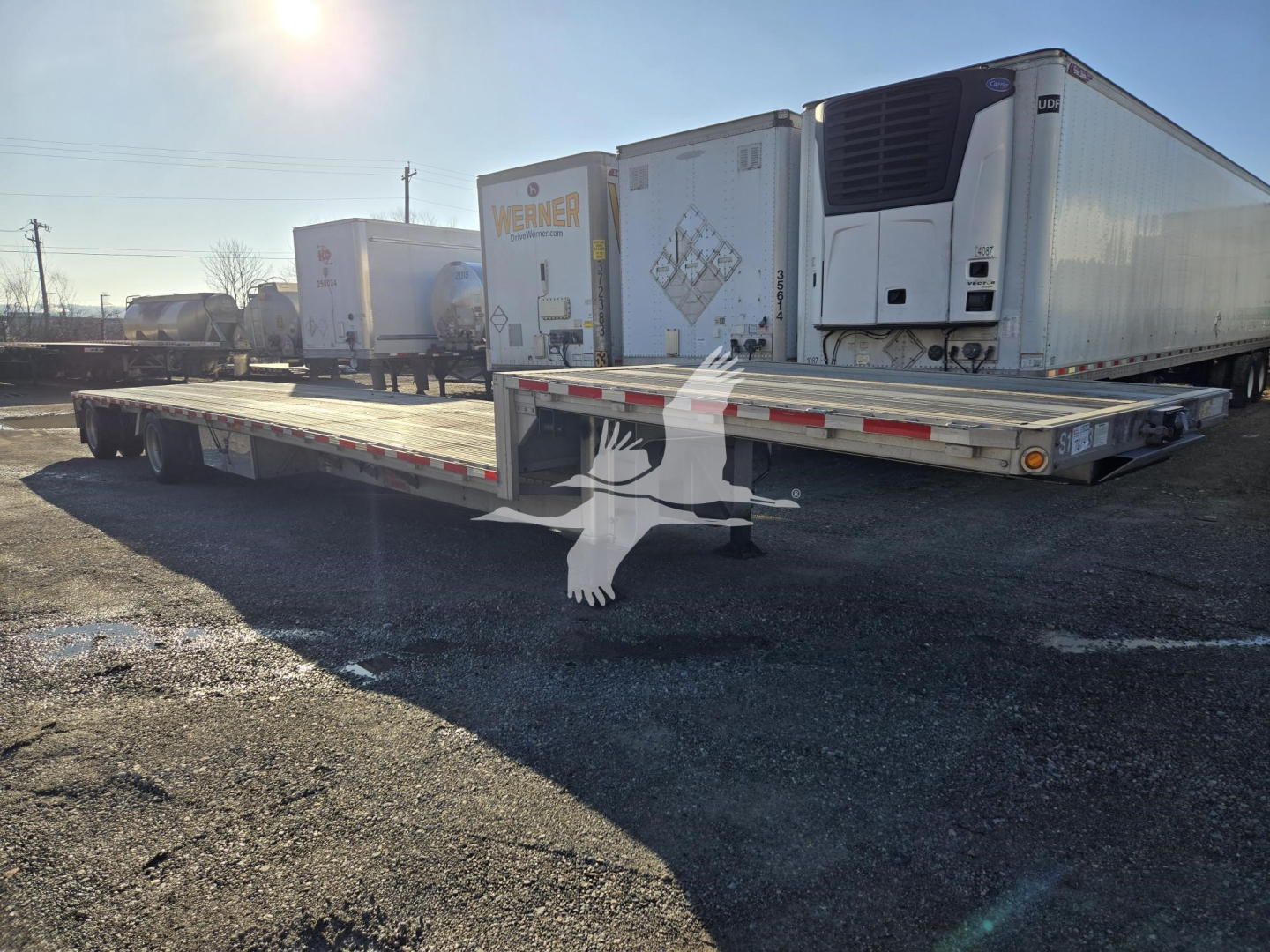 2019 Reitnouer Dropmiser trailer showing flatbed with drop deck and dual rear axles, several refrigerated trailers in background.