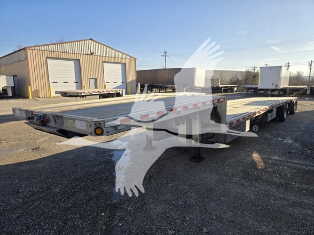 Wide view of a used 2019 Reitnouer drop deck trailer in a lot, showing a low-profile flatbed with multiple axles. No legible close text visible in the image itself.