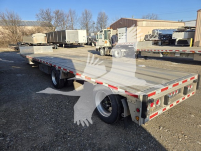 Flatbed trailer showing dropdeck with reflective safety tape and dual axles in an outdoor lot.