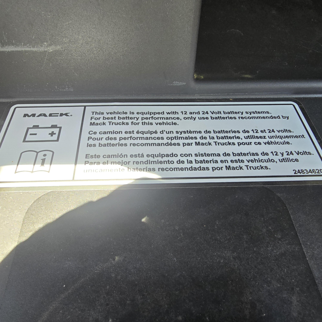 Mack label showing 12 and 24 Volt battery systems information and icons on the dash area.