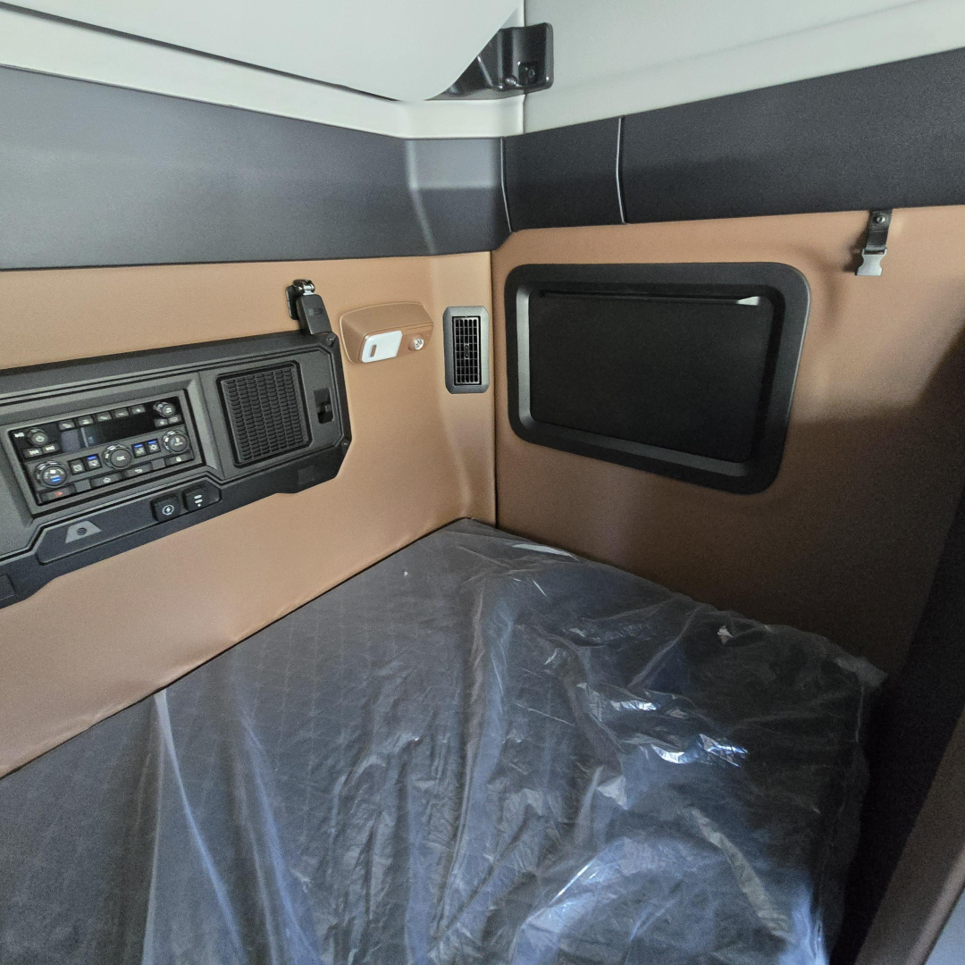 Truck cab interior showing brown and black panels, VDO dash cluster, control panel, small storage pocket; no obvious labels visible.