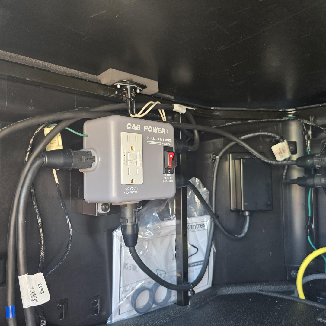 Cab power box labeled CAB POWER with 120 VOLTS 1800 AMPS and Phillips & Ferrum, mounted inside truck cab ceiling area with wiring and a plug.