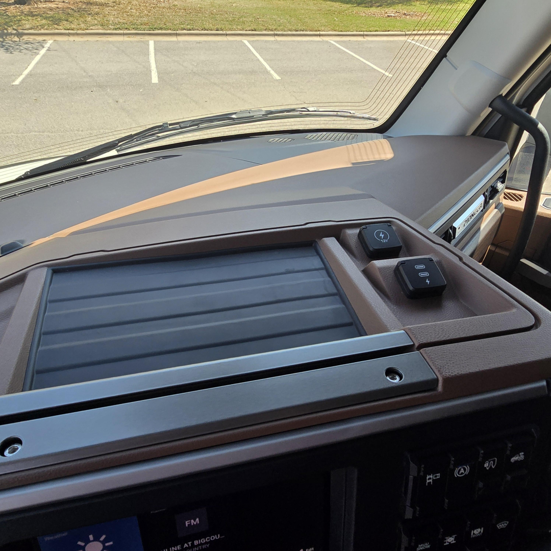 Dashboard view of 2027 Mack PR64T76M interior showing dashboard trim, console controls, and cupholder area.