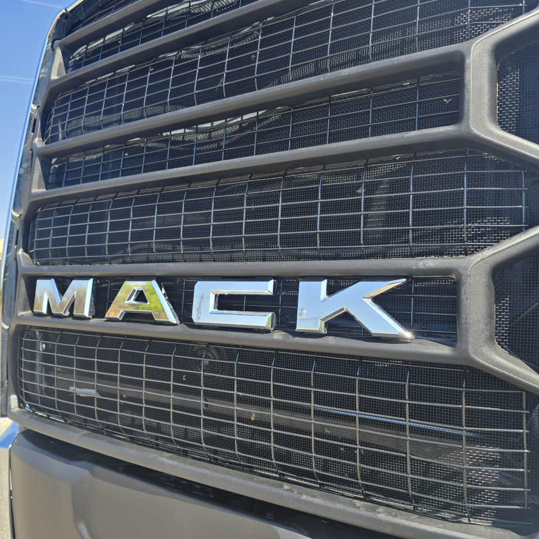 Front grille of a Mack truck showing the MACk emblem on the grill with chrome letters against a black grille.