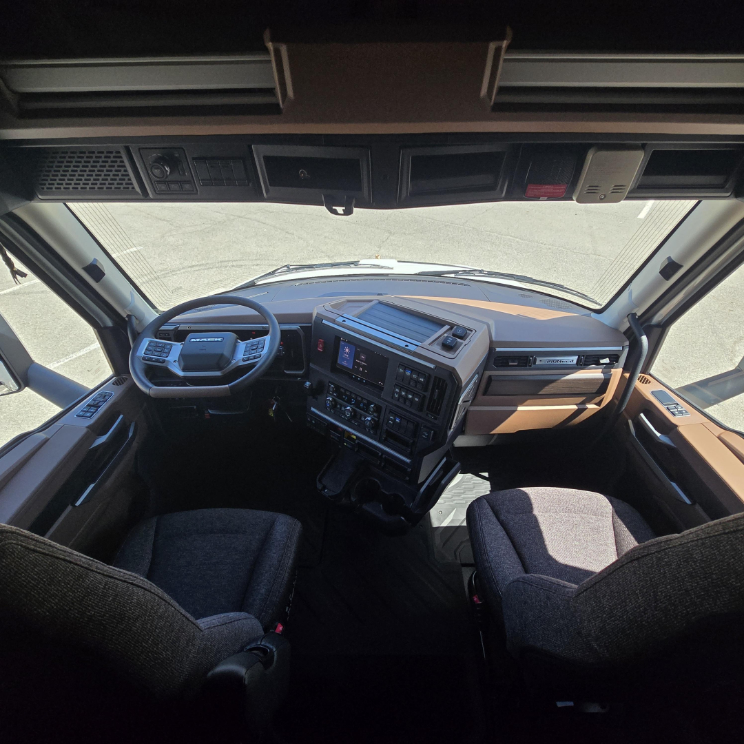 Interior cockpit view of a Mack PR64T76M truck showing steering wheel, dashboard, and center console.