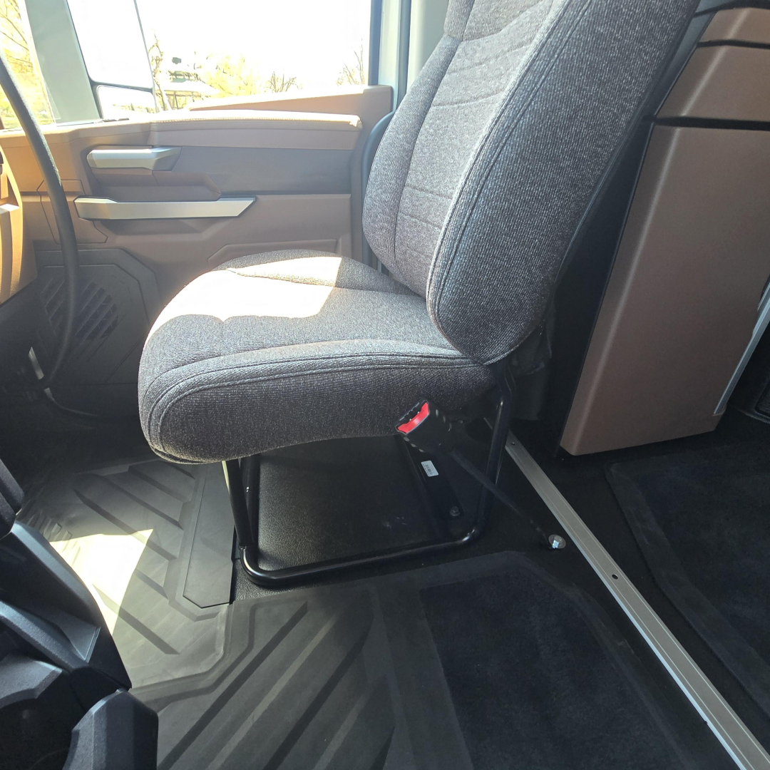 Interior cab with driver seat of 2027 Mack PR64T76M showing grey fabric seat and door panel.
