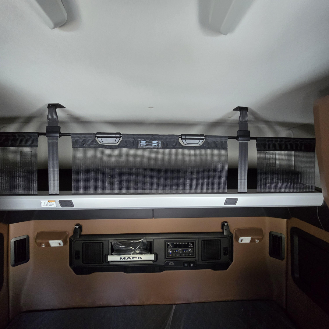 Cabin sleeper area of a 2027 Mack PR64T76M showing overhead bunk and control panel with storage pockets.