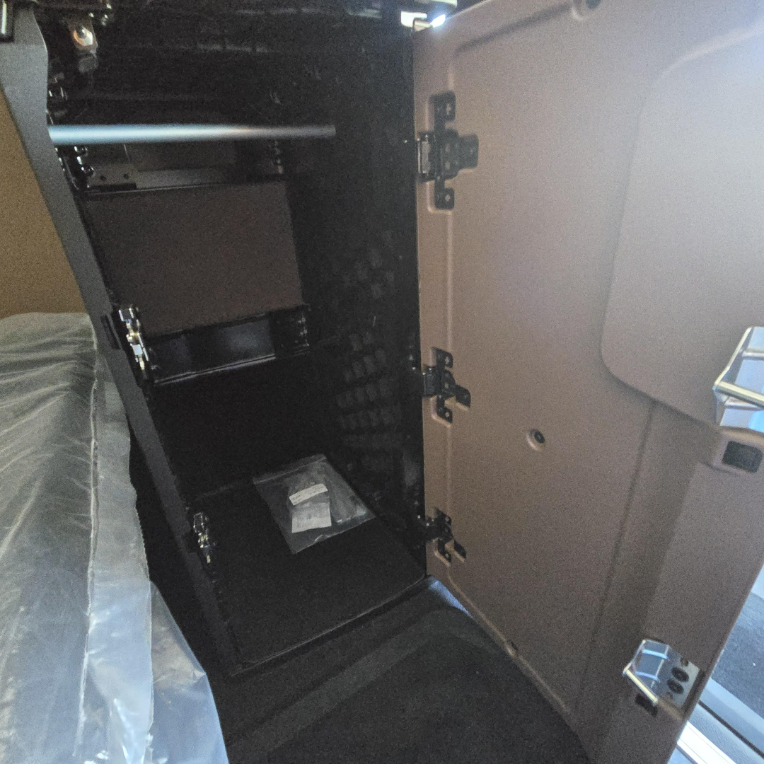 Truck interior showing storage cabinet with shelves and a small bag placed on the bottom shelf.