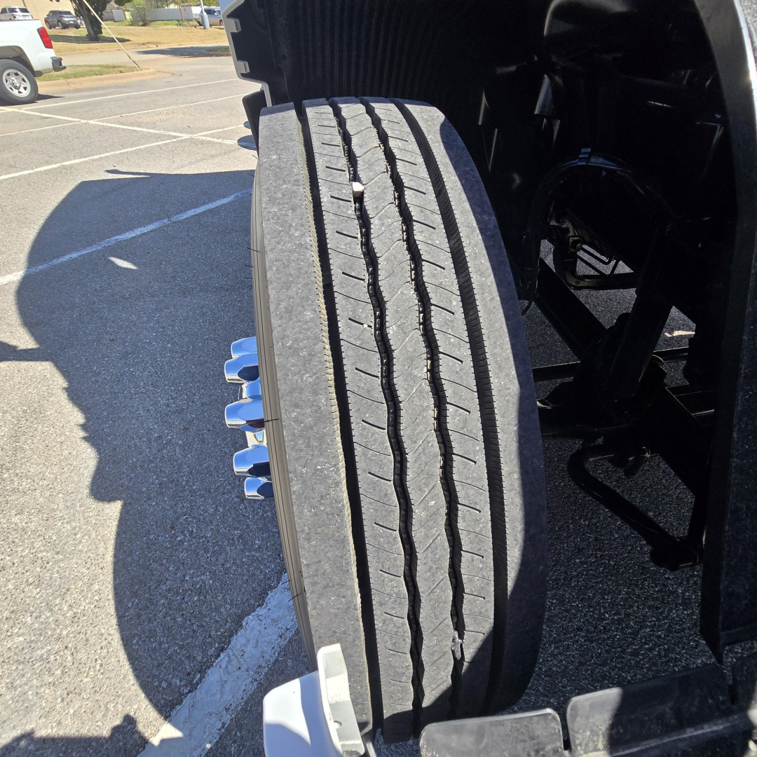 Tire tread view of a new Mack PR64T76M truck showing front dual tires and wheel components.