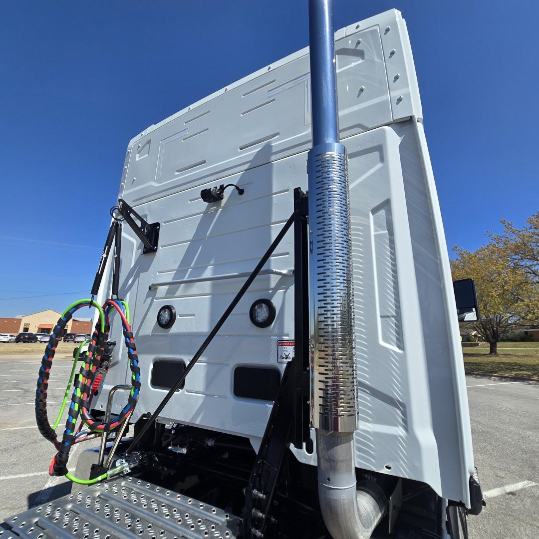 Truck cab rear view showing exhaust stack and back of sleeper with cables and air lines.