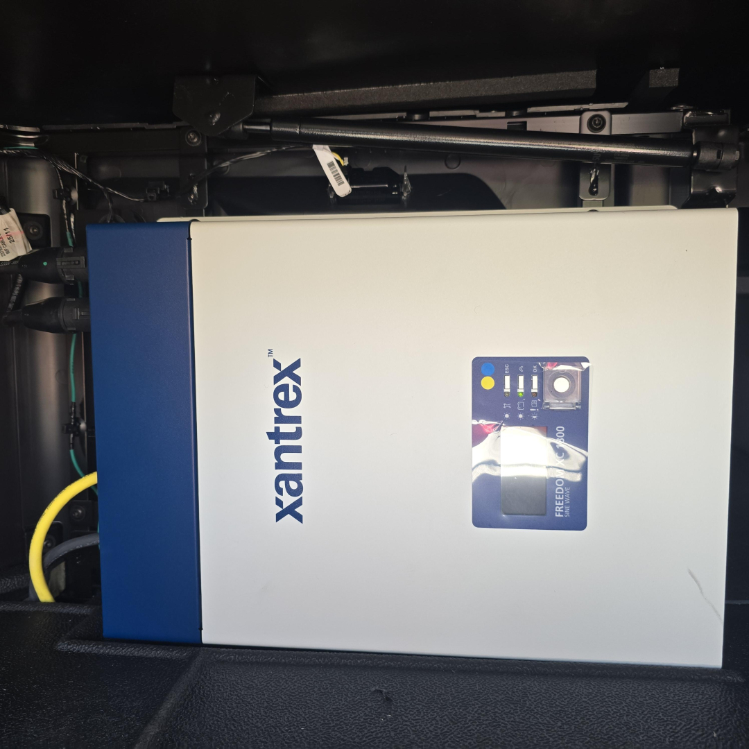 Xantrex inverter mounted in truck engine bay with blue-and-silver housing and control panel visible.