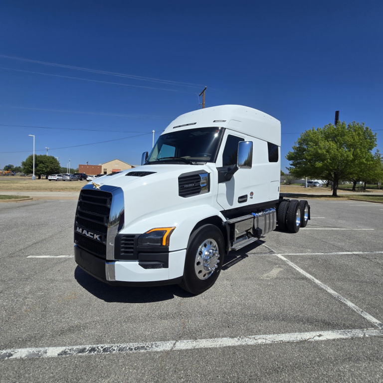 Mack PR64T76M conventional sleeper truck in white from left front view in a parking lot. Visible text: MACK on grille, no other legible labels.