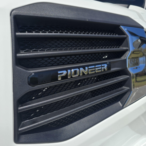 Front grille of a white Mack truck showing 'PIONEER' emblem and horizontal slats.
