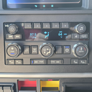 Mack PR64T76M dash cluster showing radio display 97.5 FM and 64°F cabin temp, control knobs, climate and media buttons.