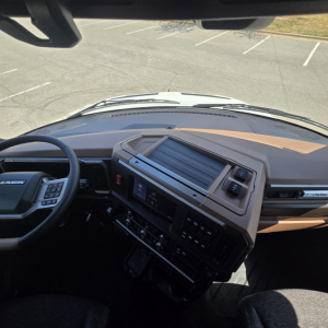 Dashboard and steering wheel area of a Mack truck cab interior with center console and instrument display.