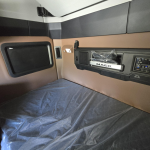 Mack PR64T76M sleeper cab interior showing side storage, control panel, and dash with Mack badge.
