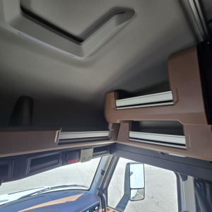 Cab interior overhead storage compartments in a Mack PR64T76M sleeper cab with brown panels and sliding rails.