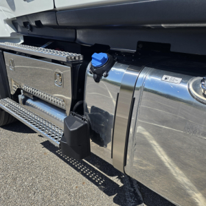 Truck side view showing chrome fuel tank with blue filler cap, polished steps, and side storage box on Mack PR64T76M.
