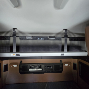 Cabin sleeper area of a 2027 Mack PR64T76M showing overhead bunk and control panel with storage pockets.