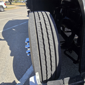 Tire tread view of a new Mack PR64T76M truck showing front dual tires and wheel components.
