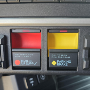 Trailer air supply and parking brake controls in a Mack PR64T76M cabin showing red and yellow control levers.