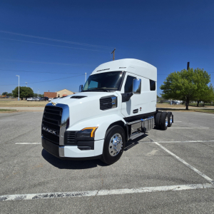 Mack PR64T76M conventional sleeper truck in white from left front view in a parking lot. Visible text: MACK on grille, no other legible labels.