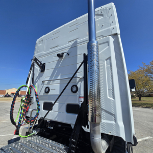 Truck cab rear view showing exhaust stack and back of sleeper with cables and air lines.