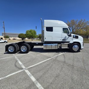 Truck chassis with tandem rear axles in-side view showing cab and fuel tanks.