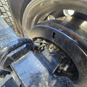 Mack PR64T76M truck component close-up showing wheel and suspension/airline hardware with hub area.