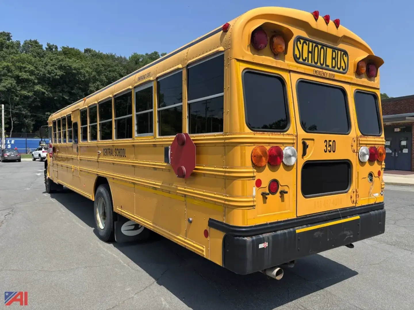 Yellow school bus rear view with 'SCHOOL BUS' sign, back doors, and red safety markings visible.