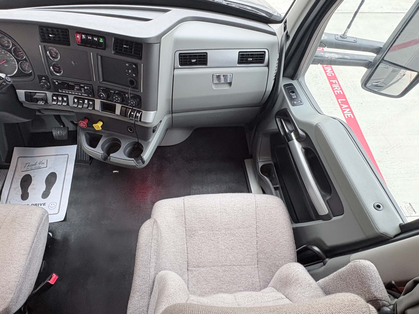 Truck cab interior of a 2022 Kenworth T680 showing driver seat, dashboard, center console, and steering area.