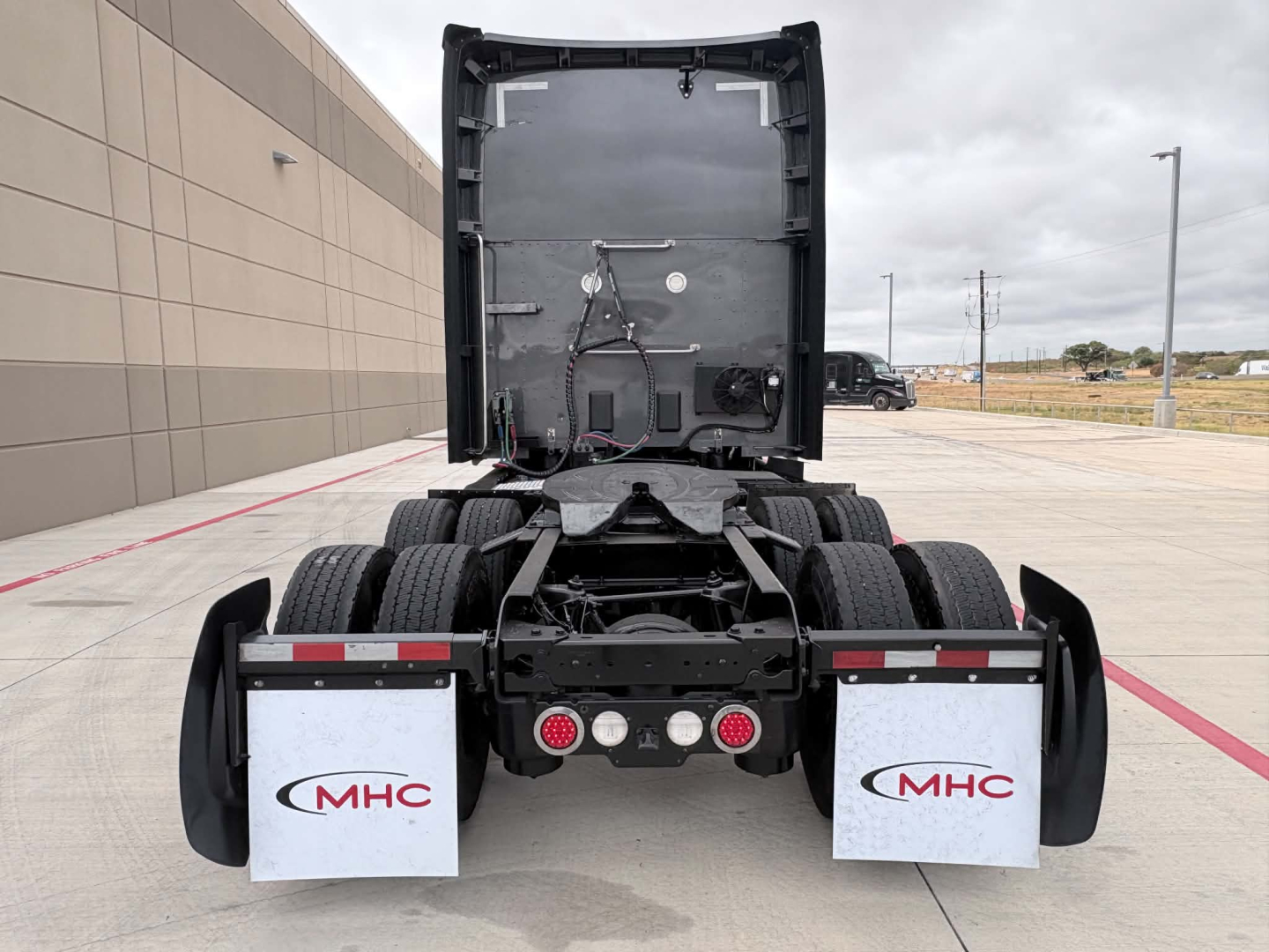 Kenworth T680 truck rear view showing fifth wheel and bumper with MHC mud flaps and taillights.