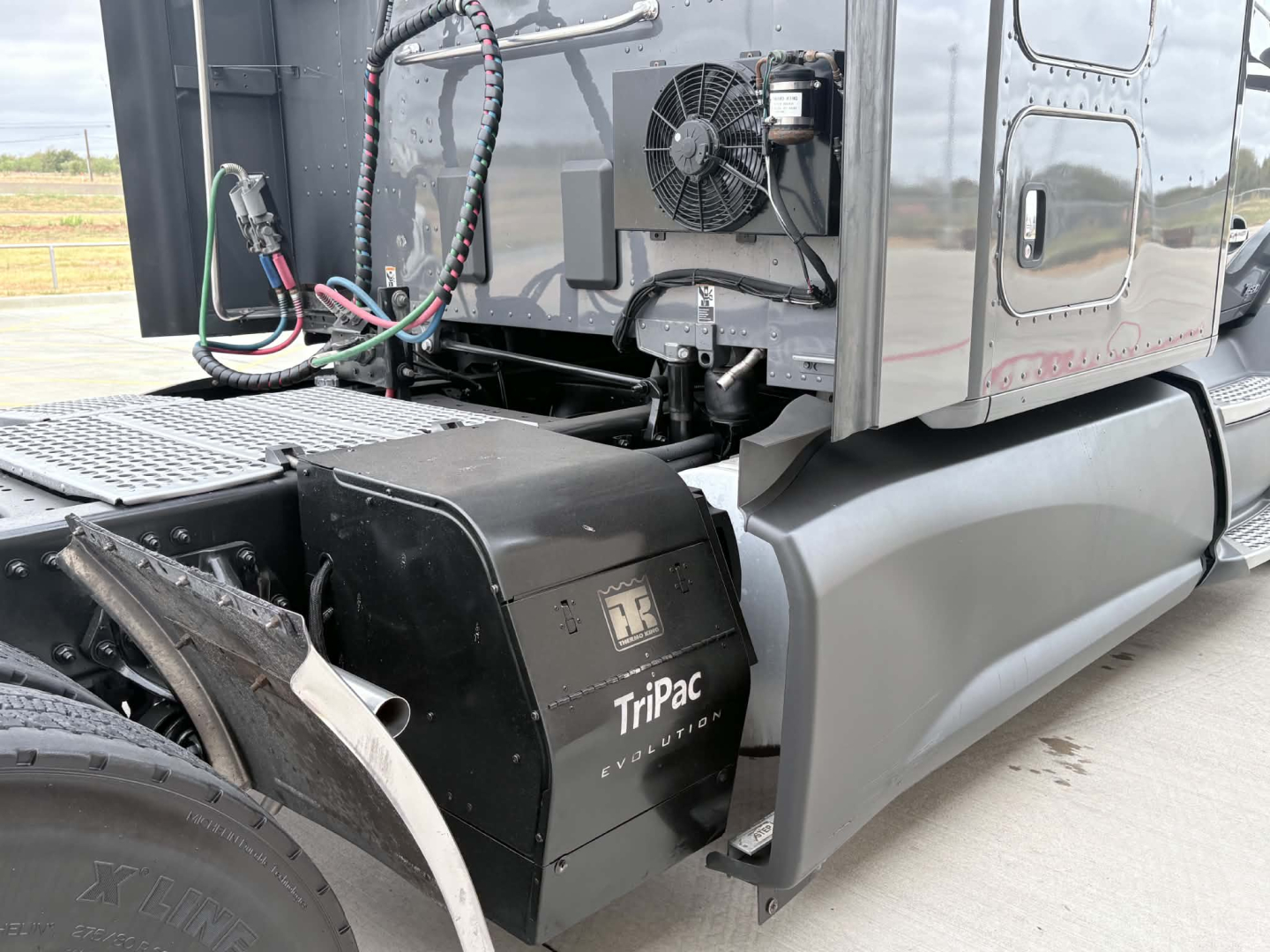 Trucks side view showing TRIPAC auxiliary power unit and air lines under cab of Kenworth T680.