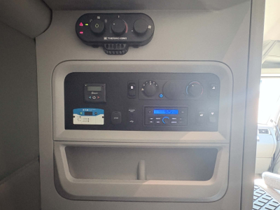 Dashboard of a Kenworth truck showing climate controls and radio unit. Visible text includes THERMO KING on a unit at top and various control labels on the panel.