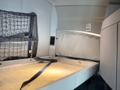 Kenworth T680 sleeper cab interior cargo area with netted storage, side panel, and window hatch visible.