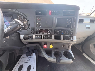 Interior dash of a Kenworth T680 truck showing gauges, steering wheel, control switches, and center console with ignition key and knobs.