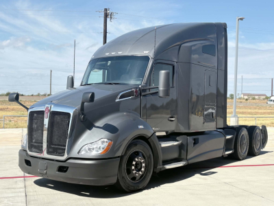 Kenworth T680 conventional sleeper truck in gray with aerodynamic cab, dual rear axles, and large side mirrors.