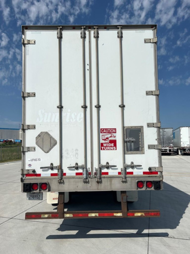 Rear view of a utility van trailer showing double doors with hinges, latches, red reflective tape, and caution sticker.