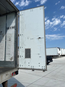 Trailer rear door of a 2014 utility van trailer showing a vent and vertical riveted panels.
