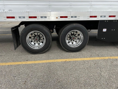 Dual rear wheels of a refrigerated trailer with chrome rims, black mudguard, and side panels visible
